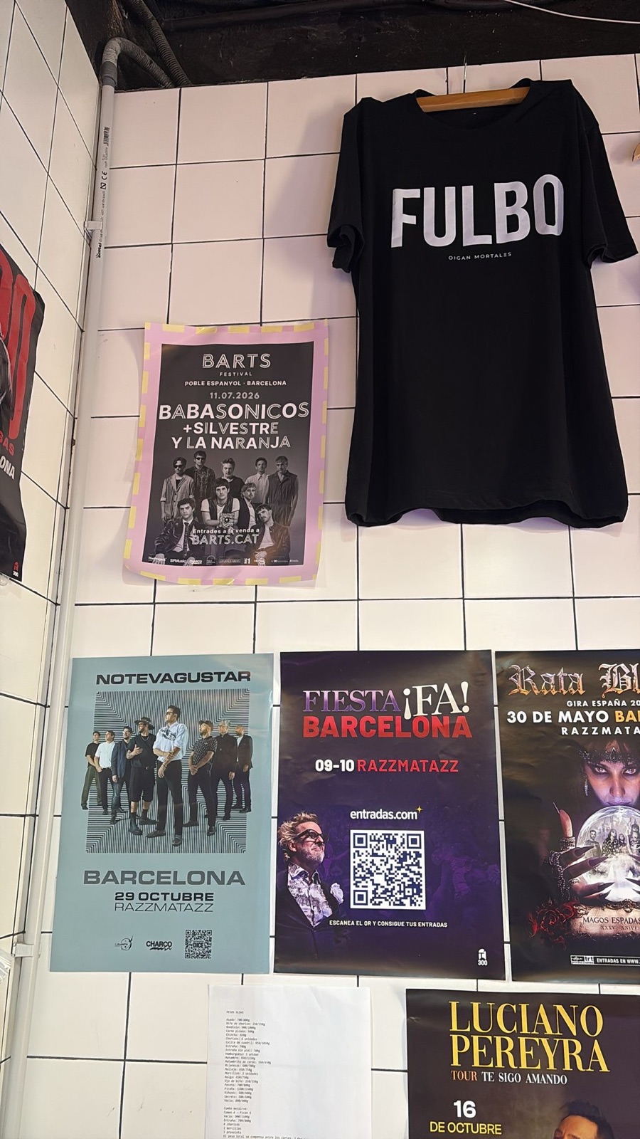 Carteles de conciertos pegados en la pared de un bar de Barcelona