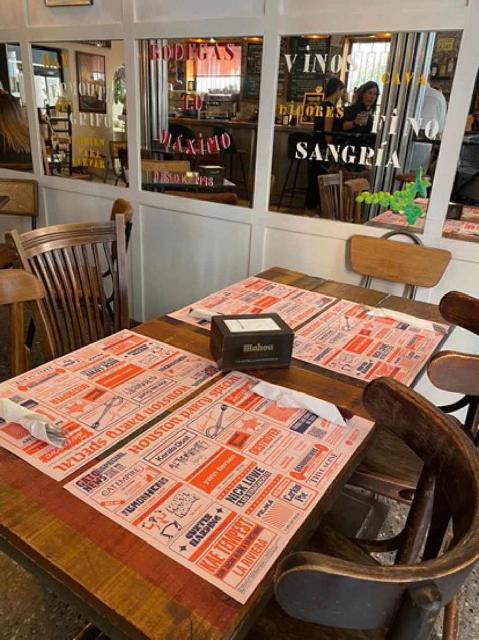 Manteles monográficos de Houston Party de Gato News en las mesas de un restaurante
